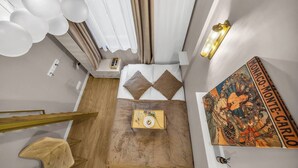 A hotel room with a bed, a bedside table with a book, a small stool, a wall-mounted light, and a poster. - Warsaw Praga Studio – Central Access & Parking (Warszawa)