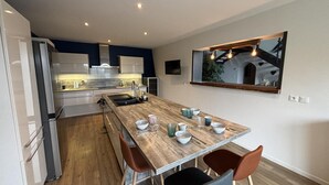 Une cuisine moderne avec une table à manger en bois, quatre chaises et un grand miroir au-dessus de la table.