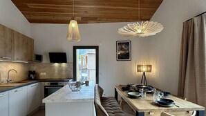 A modern kitchen with a central island, wooden ceiling, and pendant lighting.