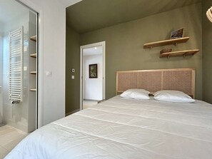 A bedroom with a bed, a wooden headboard, a white door, and a hallway. - New 4-room apartment for 6 people with terrace in Briançon (Briançon)