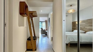 A modern hotel hallway with a wooden staircase, a bed with a wooden headboard, and a large window.