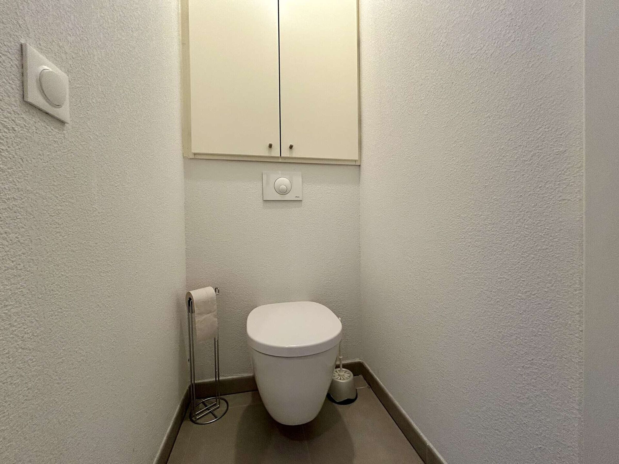 Pieni, siisti kylpyhuone, jossa on wc, wc-paperiteline ja bidee.