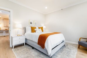 Un dormitorio moderno con cama, mesitas de noche y un escritorio.