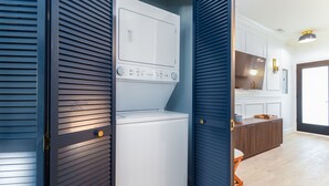 Une buanderie équipée d’un lave-linge et d’un sèche-linge, de meubles de rangement en bois et d’un plan de travail avec un évier.