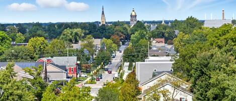 A town with a prominent church steeple and a large dome, surrounded by residential buildings and lush greenery.