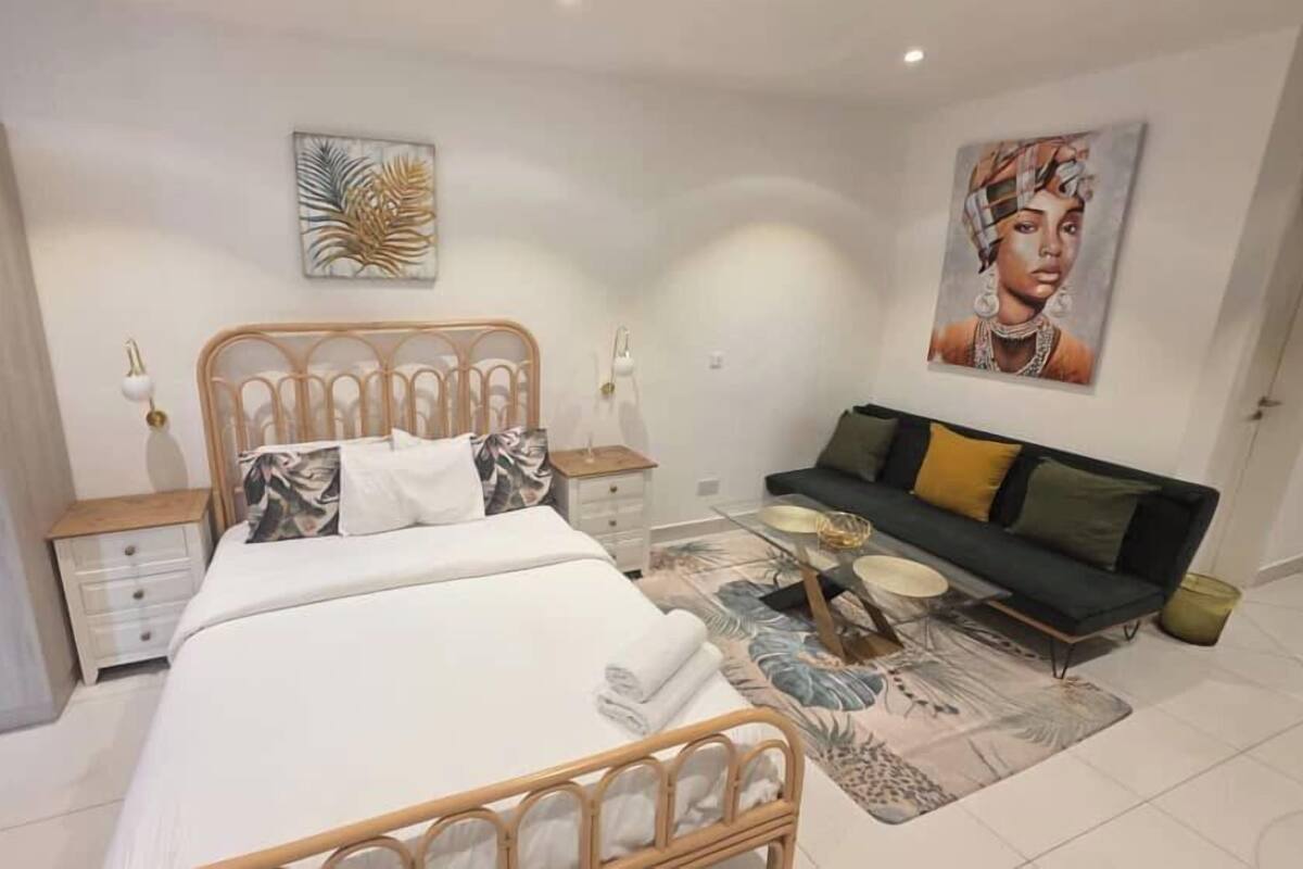 A bedroom with a bed, a nightstand, a sofa, and a wardrobe.