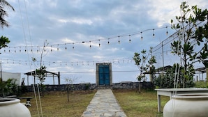 A stone pathway leading to a blue door, surrounded by a fence and string lights.