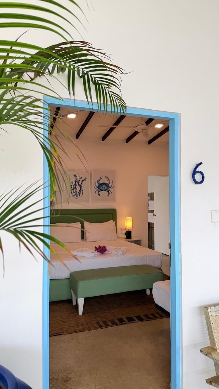 A bedroom with a bed, a nightstand, a green bench, and a wall number 6.