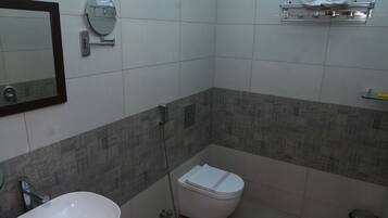 A bathroom with a sink, toilet, shower, and a towel rack.