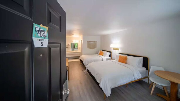 Ett hotellrum med två sängar, ett skrivbord och en stol.