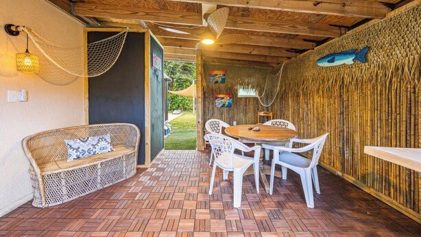Un espacio exterior acogedor con mobiliario de mimbre, una mesa de madera y sillas.