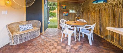 Un espace extérieur accueillant, aménagé avec des meubles en osier, une table en bois et des chaises.