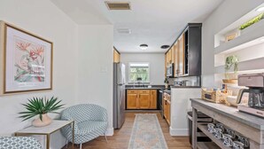 Una cocina compacta con armarios de madera, microondas integrado y cafetera en la encimera.