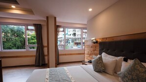 A hotel room with a large bed, a wooden headboard, and a view of the city through large windows. - Avianna Gangtok Prime Hotel & Spa  (Gangtok)