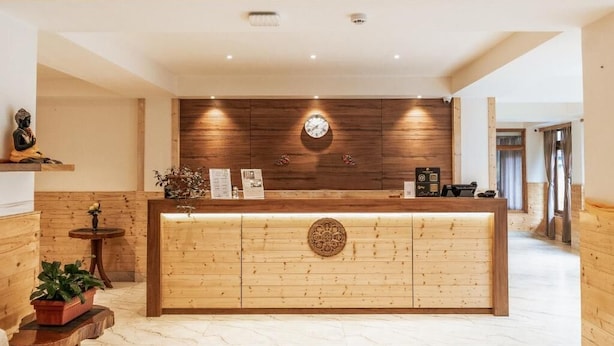 A reception desk with a wooden finish, a clock, and a small plant on the left. - Avianna Gangtok Prime Hotel & Spa  (Gangtok)