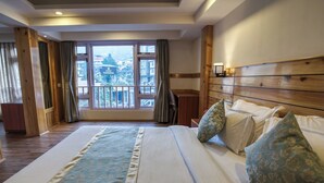 A hotel room with a large bed, wooden headboard, and a view of a police headquarters building through the window. - Avianna Gangtok Prime Hotel & Spa  (Gangtok)
