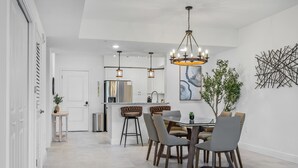 Uma cozinha moderna com uma ilha central, iluminação pendente e um espaço de jantar com mesa redonda e cadeiras.