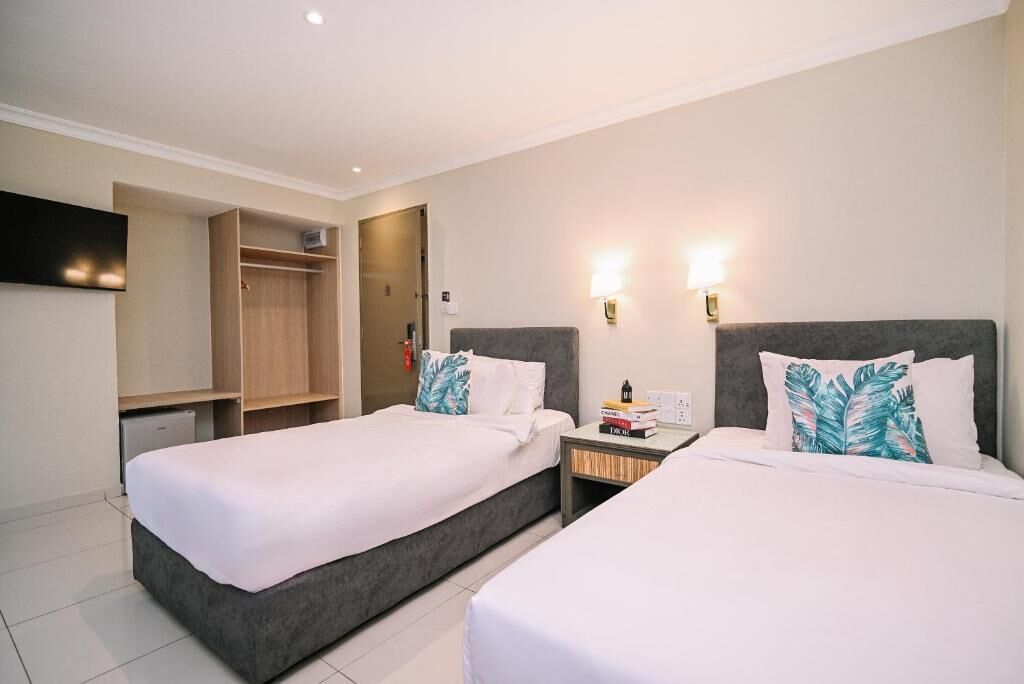 A hotel room with two beds, a wardrobe, a TV, and two bedside lamps.