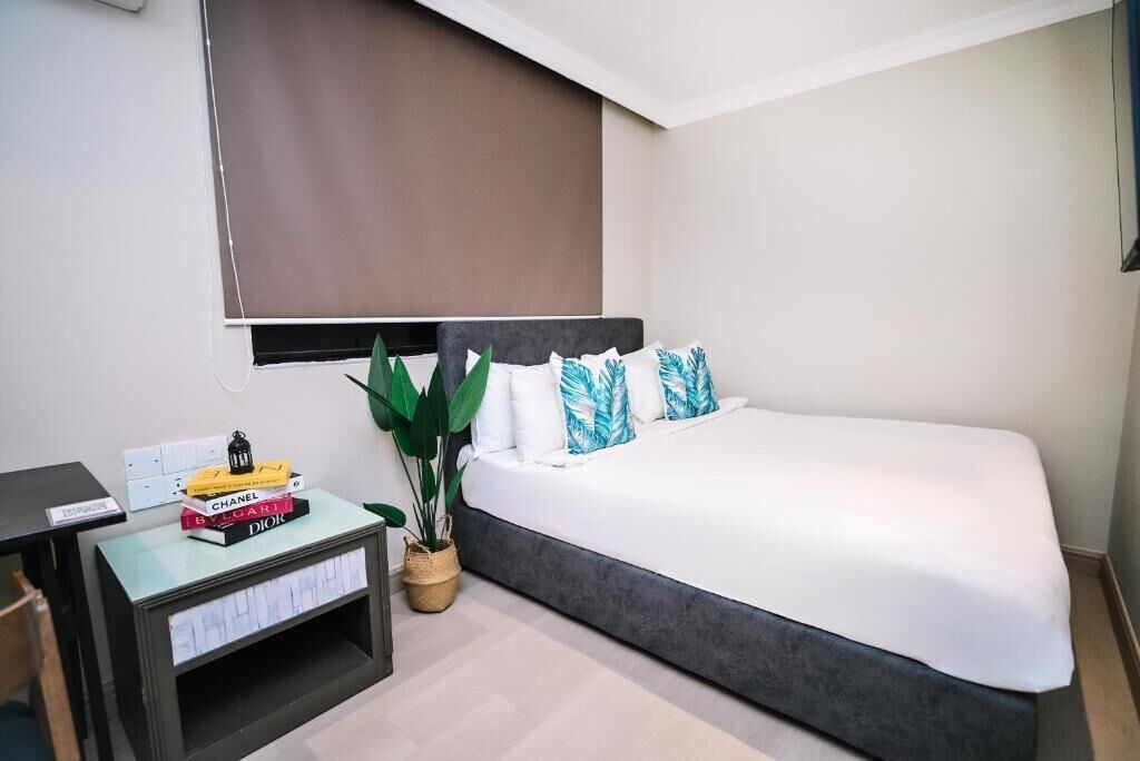 A hotel room with a bed, a desk, and a potted plant.