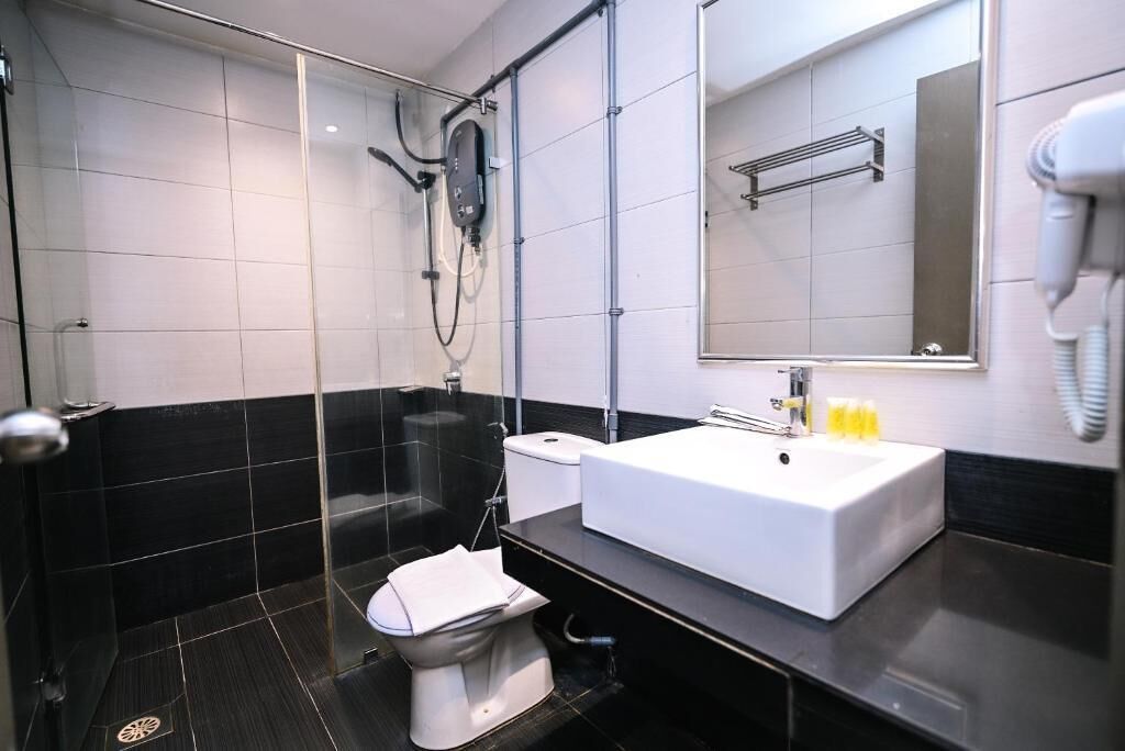 A modern bathroom with a glass-enclosed shower, a white sink, and a toilet.