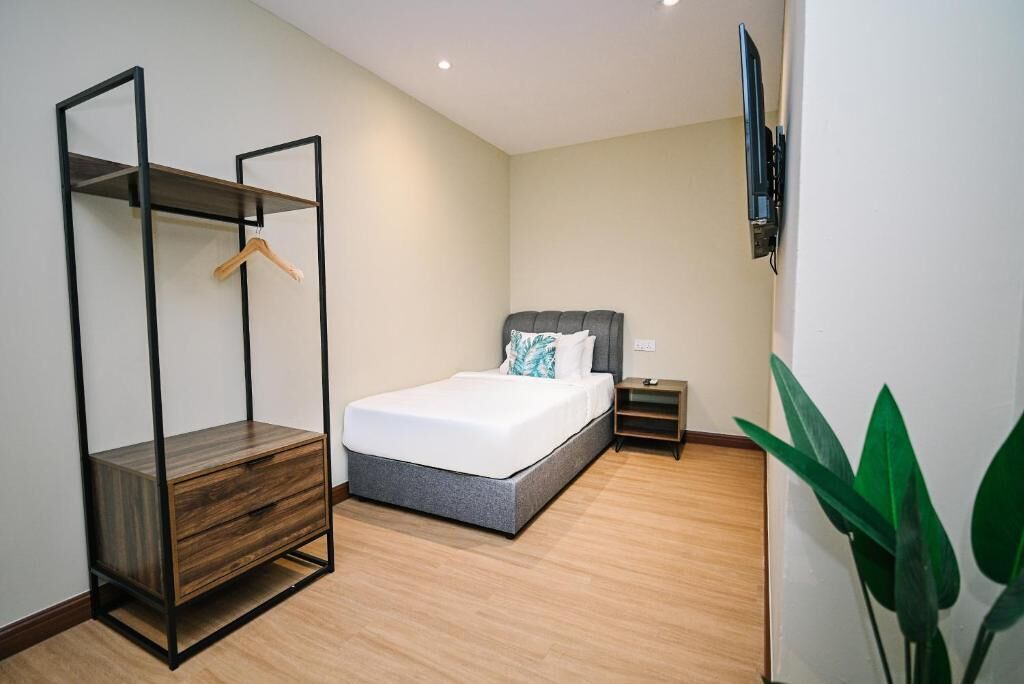 Une chambre à coucher avec un lit, une armoire en bois, une table de chevet, un téléviseur et une plante.