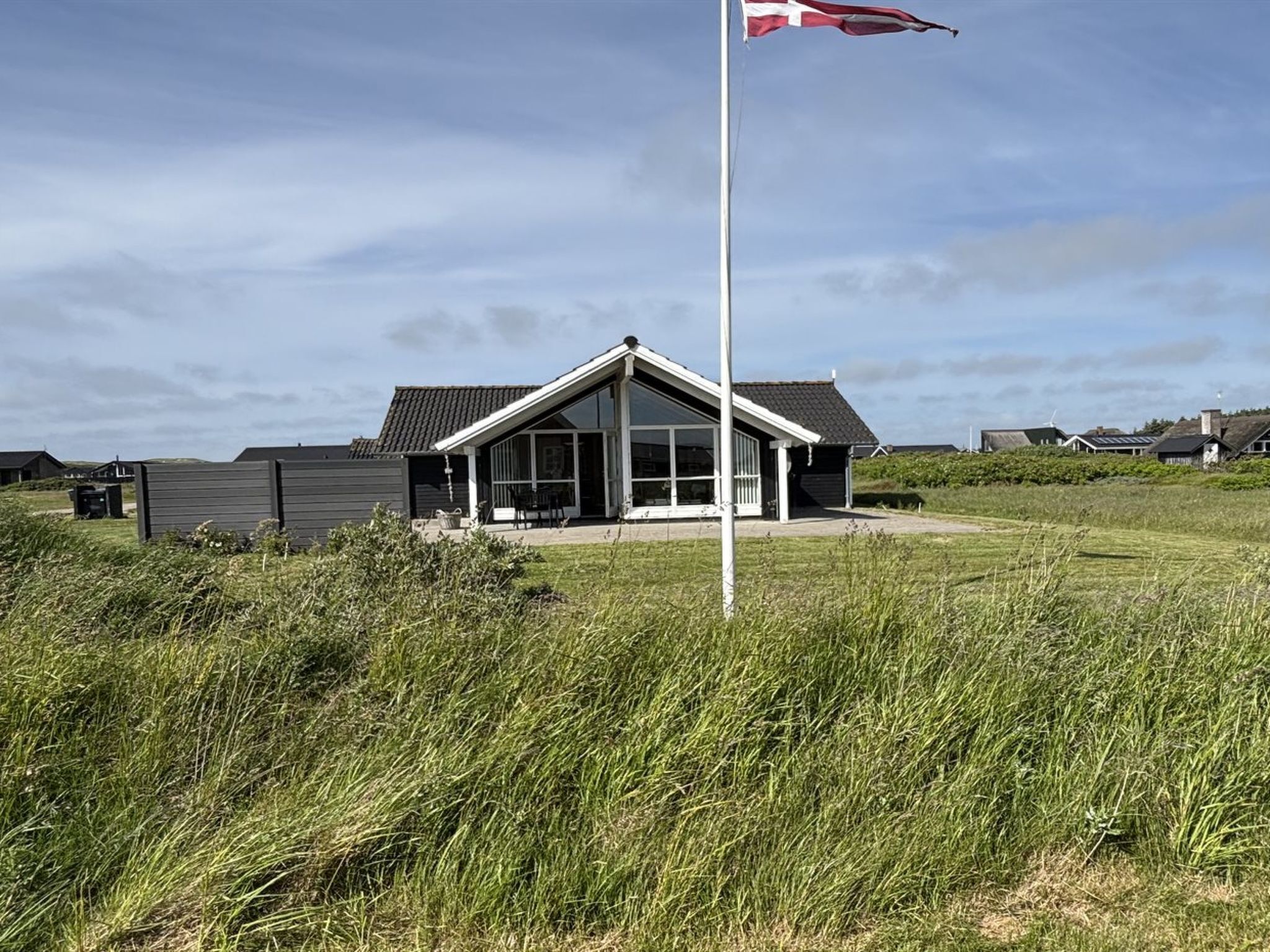 Un bâtiment moderne doté d’un toit en pente, de grandes fenêtres et d’un mât pour drapeau.