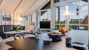 A modern interior with a dining area, a sofa, a TV, and large windows offering a view of the outside. - "Bryngeir" - 100m from the sea by Interhome (Harboøre)