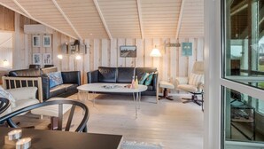 A cozy room with a wooden ceiling, a round coffee table, a sofa, and a chair. - "Bryngeir" - 100m from the sea by Interhome (Harboøre)