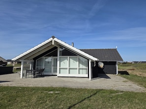 Une maison moderne dotée d’une grande baie vitrée, d’un patio couvert et d’une cheminée.