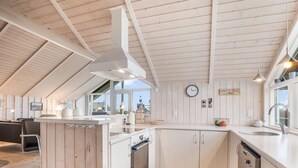 A modern kitchen with wooden beams, white cabinetry, and a central island. - "Bryngeir" - 100m from the sea by Interhome (Harboøre)