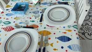 A dining table set with plates, cutlery, and glasses, covered with a tablecloth featuring a fish pattern. - Tramonti d' alba bed and breakfast (Terrasini)