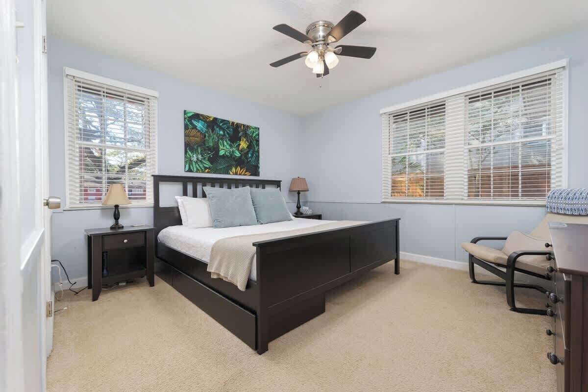 A bedroom with a bed, two nightstands, a ceiling fan, and a chair.