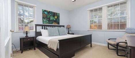 A bedroom with a bed, two nightstands, a ceiling fan, and a chair.