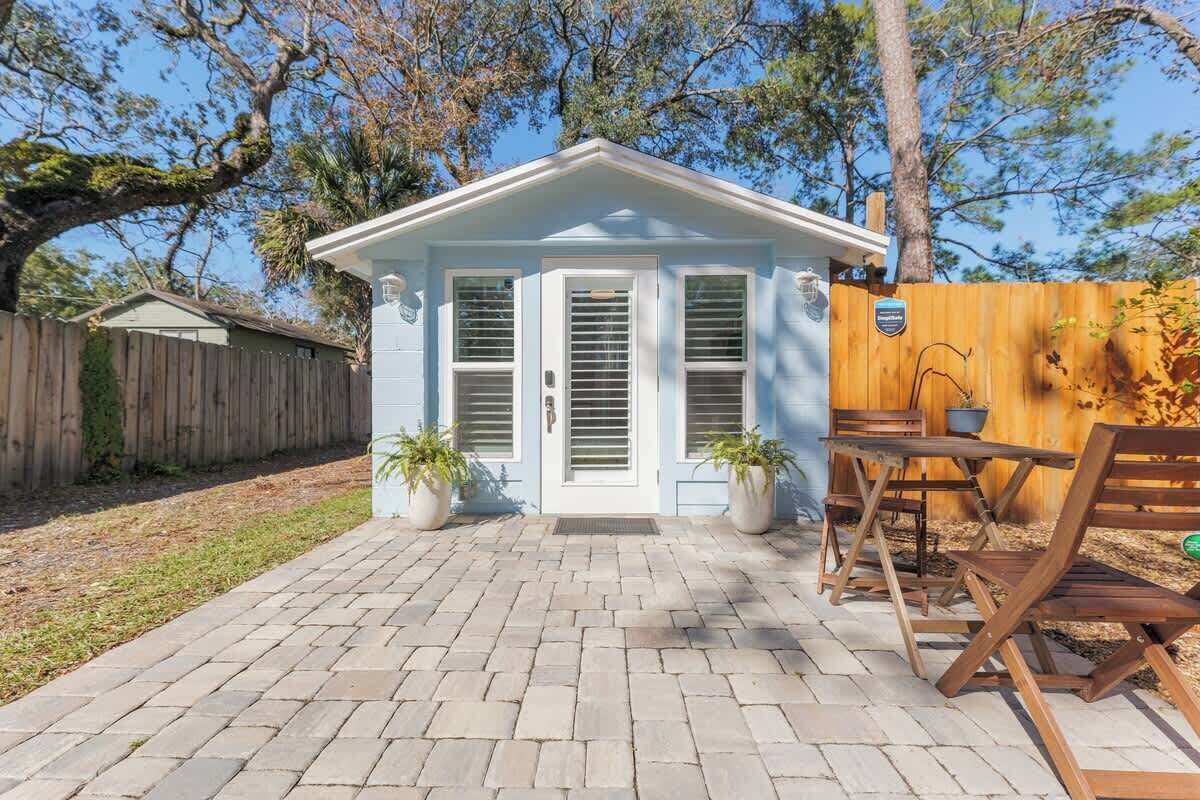A small, light blue house with a front door, two windows, and a brick patio.