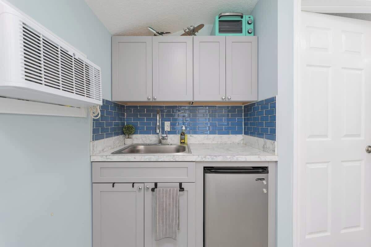 A compact kitchen with a sink, a dishwashing unit, and cabinets.