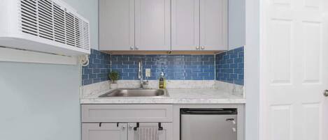 A compact kitchen with a sink, a dishwashing unit, and cabinets.