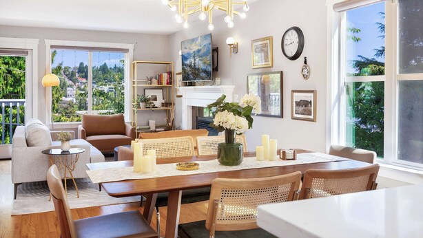 Uma sala de estar moderna com área de jantar, janelas amplas e um candelabro.