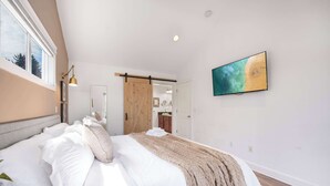 Quarto com cama grande, porta deslizante, luminária na parede e um quadro.