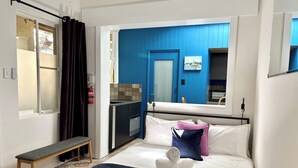 A hotel room with a bed, bench, and a view of the city through a window. - Balmain Village Retreat | Sleeps 3 | Parking | City 3kms (Balmain)