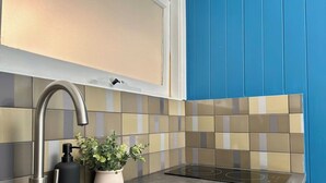 A modern kitchen with a stainless steel faucet, a black soap dispenser, and a potted plant. - Balmain Village Retreat | Sleeps 3 | Parking | City 3kms (Balmain)