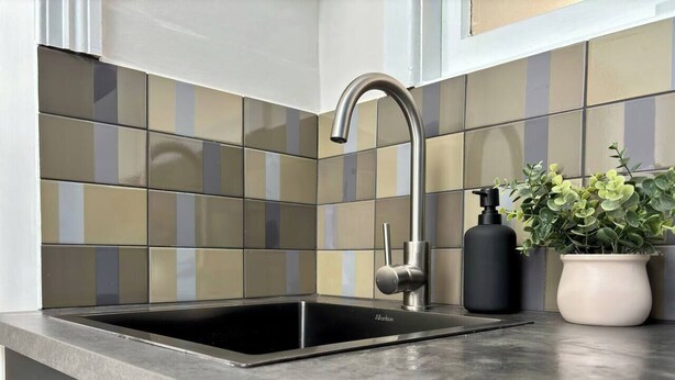 A kitchen with a modern stainless steel sink, a black faucet, and a potted plant on the counter. - Balmain Village Retreat | Sleeps 3 | Parking | City 3kms (Balmain)