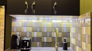 Eine moderne Küche mit einem schwarzen Schrank, einer Edelstahl-Spüle, einem schwarzen Wasserkocher und einem Toaster.