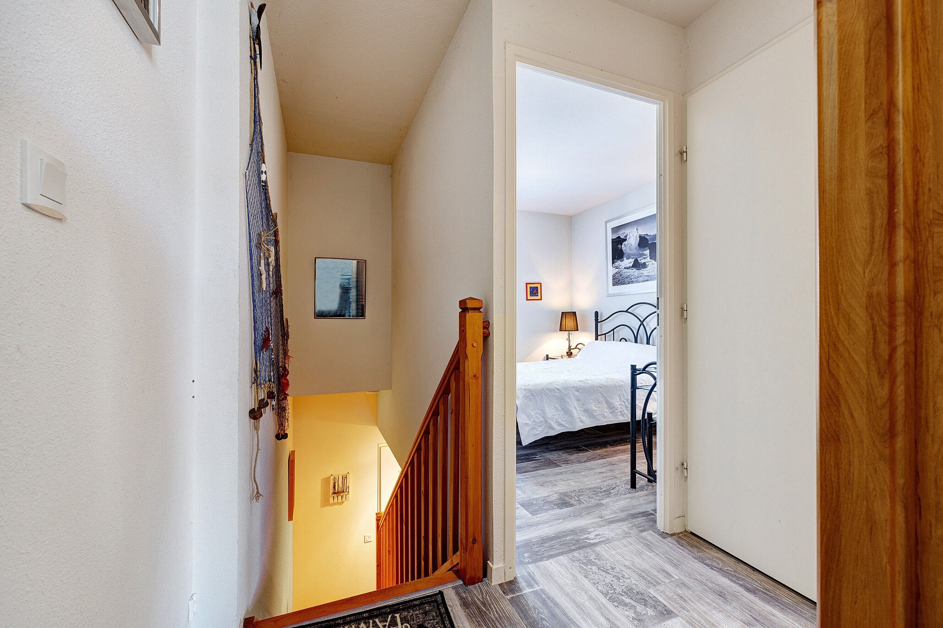 A staircase leading to a bedroom with a bed, a nightstand, and a lamp.