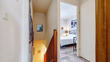 A staircase leading to a bedroom with a bed, a nightstand, and a lamp.