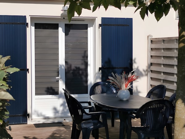 Une terrasse extérieure avec une table ronde, quatre chaises et un vase décoratif.