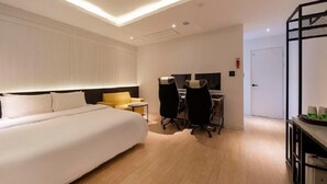Ein Hotelzimmer mit einem großen Bett, einem Schreibtisch mit zwei Stühlen und einem kleinen Tisch mit einem Sessel.