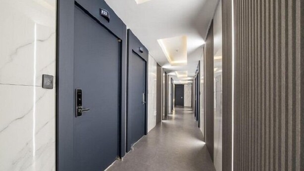 Ein moderner Hotelkorridor mit dunklen Türen, Marmorwänden und einer langen, schmalen Form.