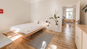 A minimalist bedroom with a wooden bed, bedside table, and a desk with a lamp. - Art & Design Parkview Apartment in Rīga (Rīga)