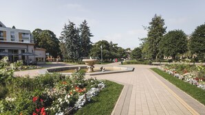 A paved pathway with a fountain and flower beds on either side. - Art & Design Parkview Apartment in Rīga (Rīga)