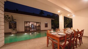 An outdoor dining area with a pool, a dining table set for six, and a building entrance in the background. - Idda Bouqtiue Villa  (Ahangama)